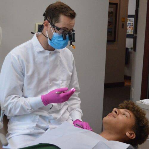 male dentist preparing to treat a teenage male patient