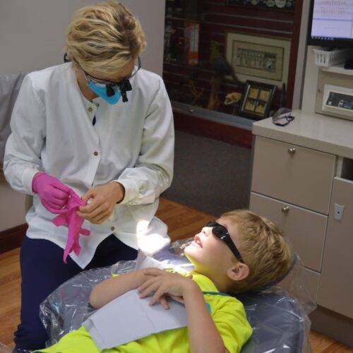 a female dentist preparing to treat a young male patient